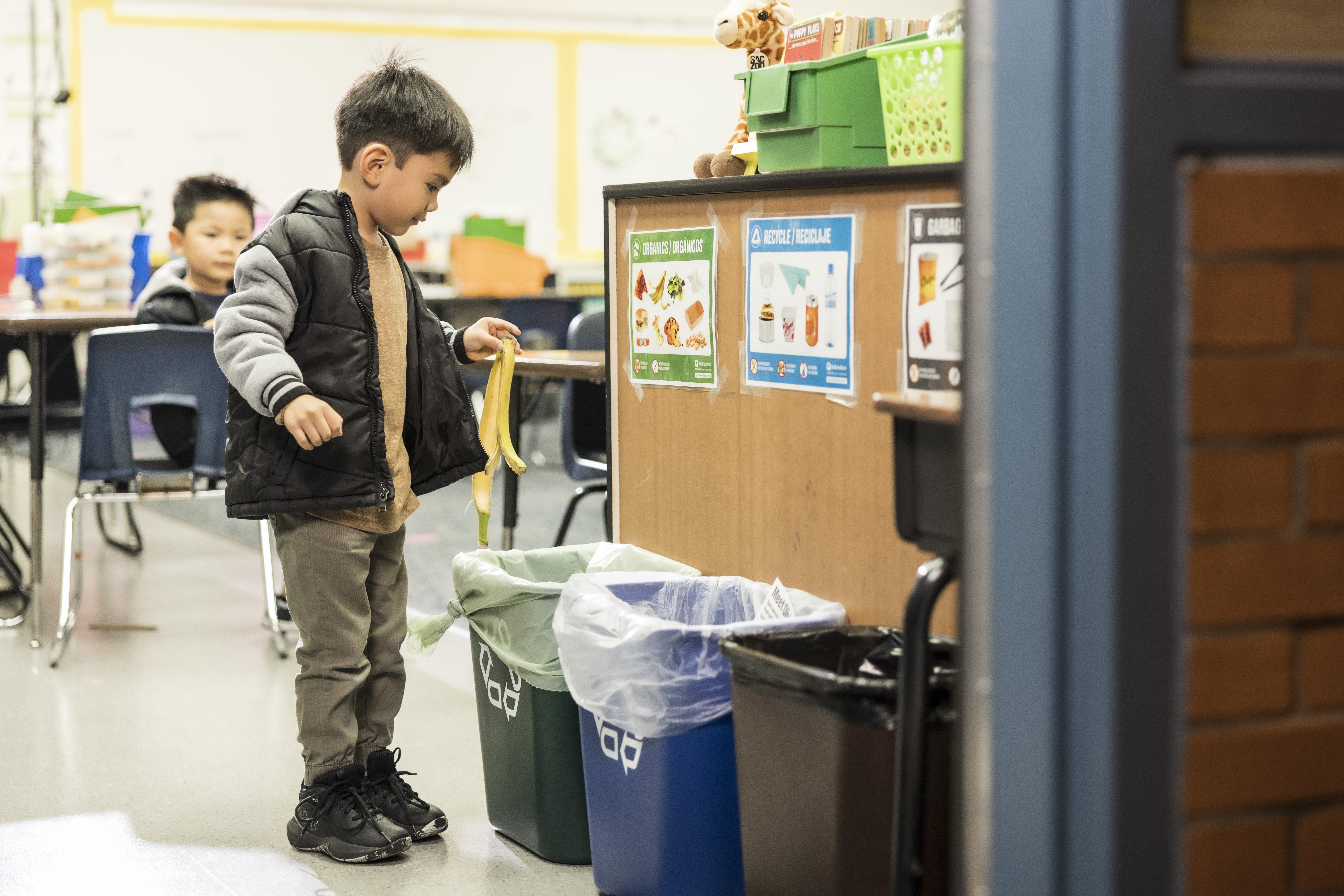 Student using a classroom organics bin to recycle his banana peel.
